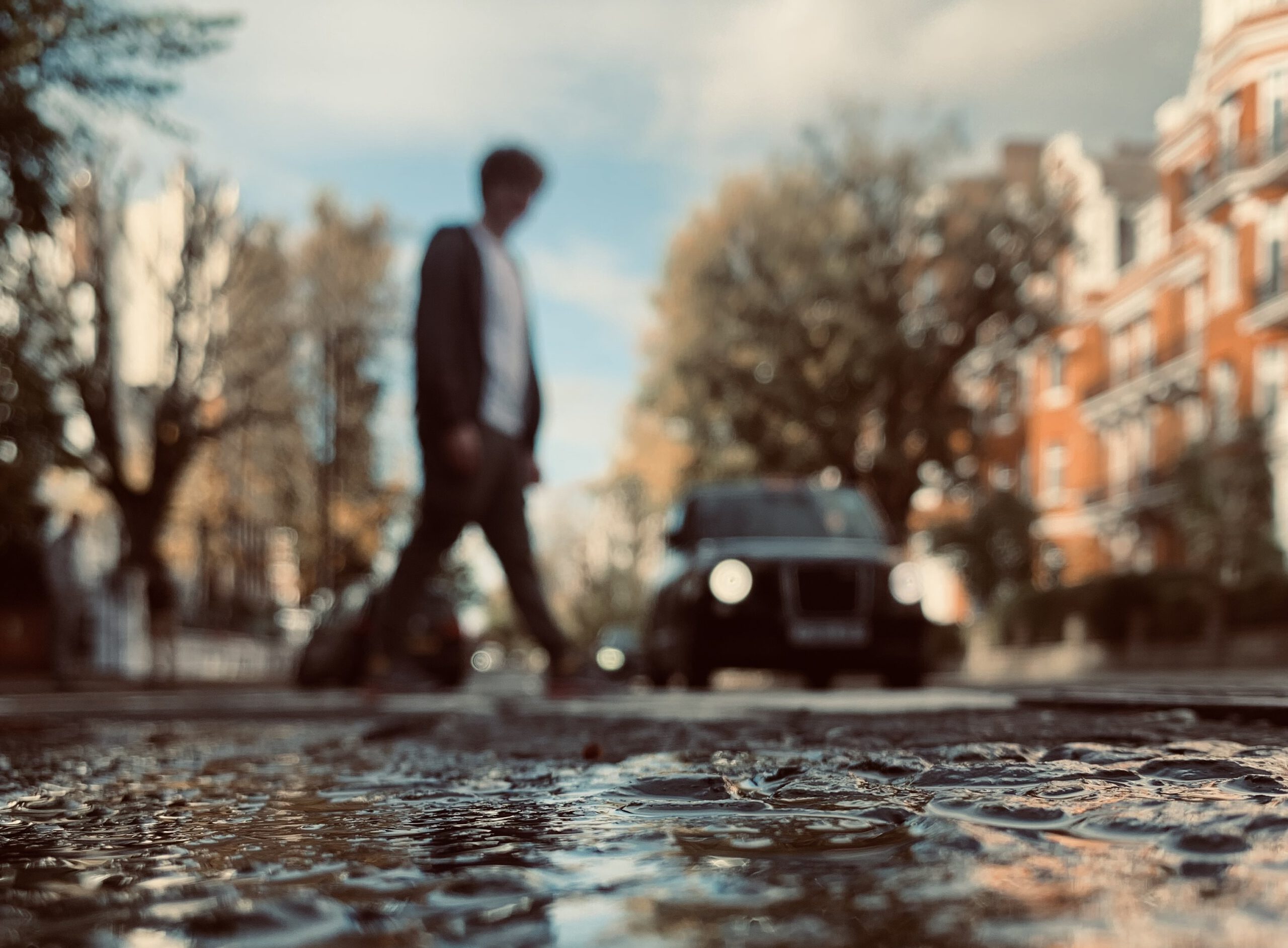 Person walking across a street crossing with a car in the background.