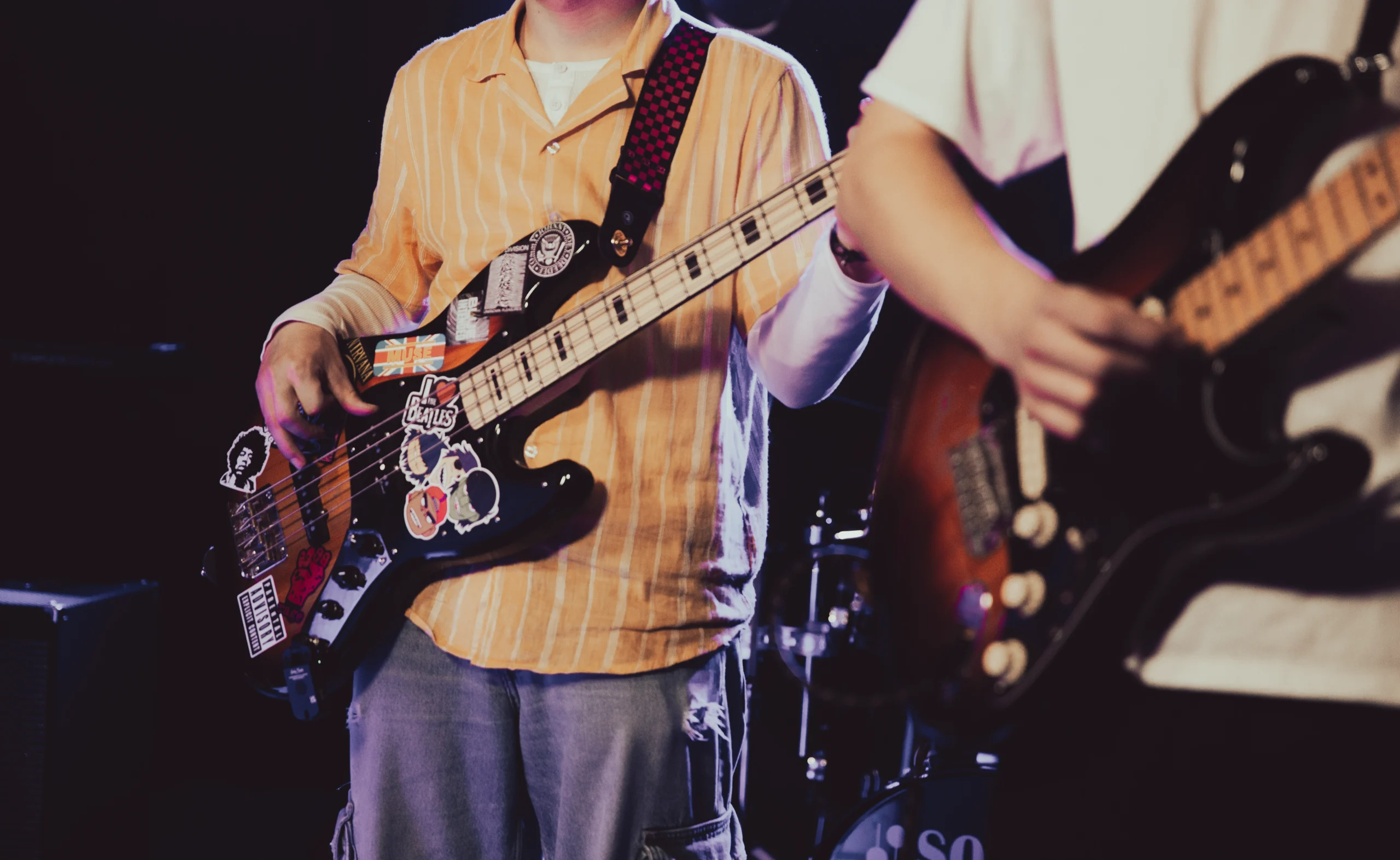 Two guitarists from Midnight Poets Club standing next to each other on stage.